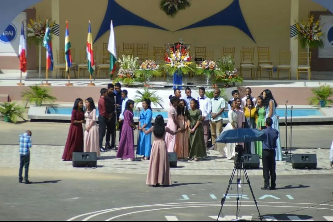 Les choristes en tenues de couleurs chantent en plein air, sur une grande esplanade